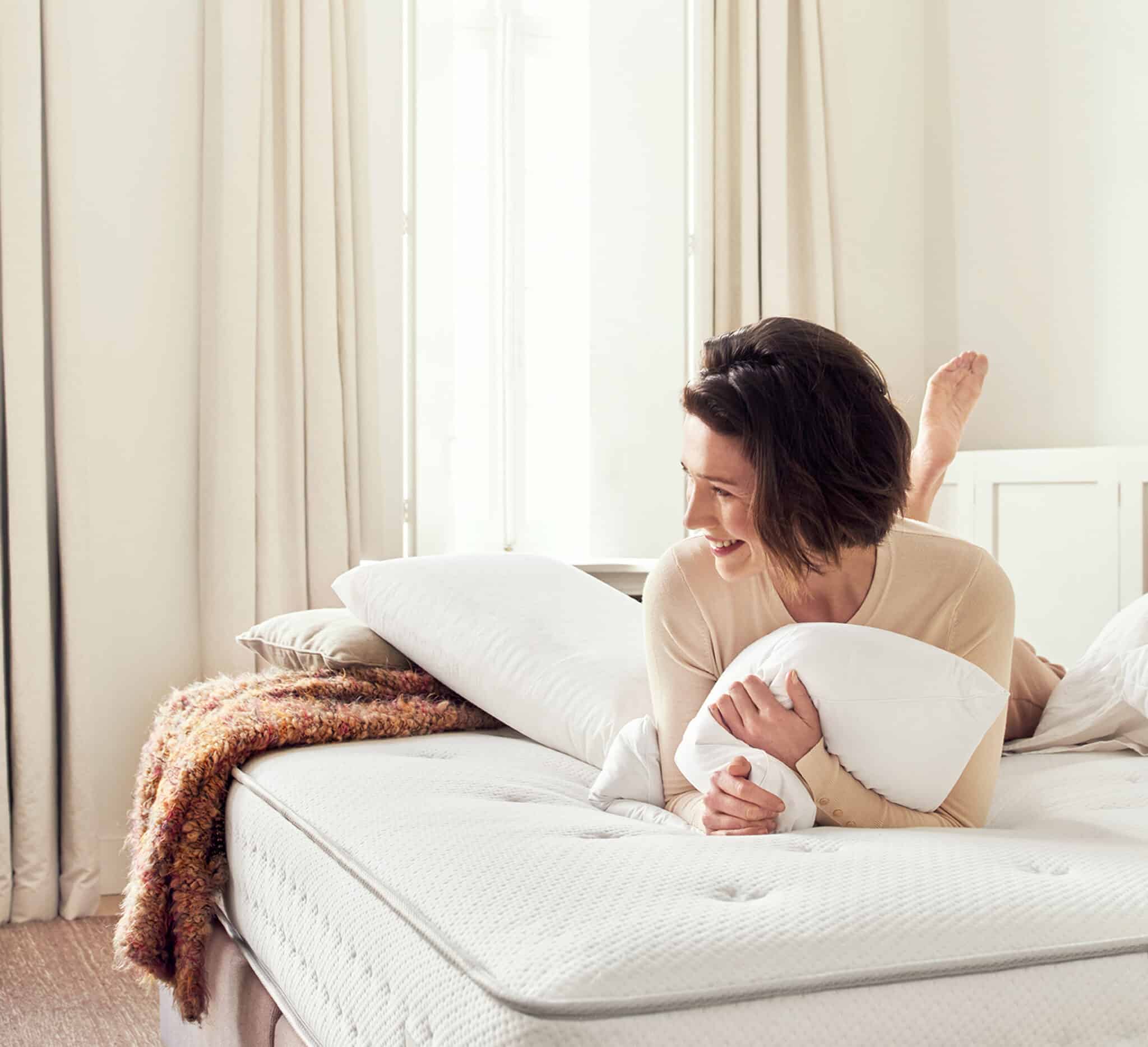 femme dans son lit qui tient son oreiller beka entre ses mains