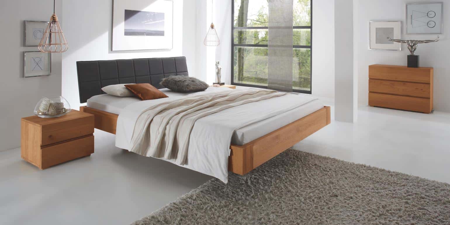 cadre de lit en bois dans une chambre blanche avec une tête de lit noir