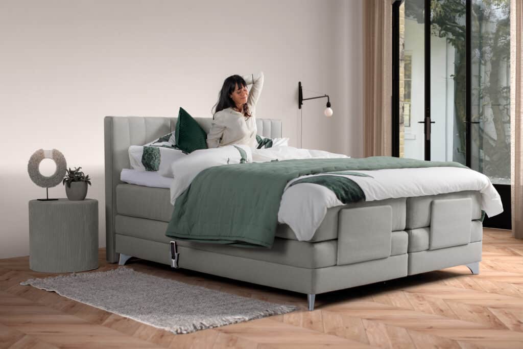 Boxspring Velda piquet 160x200 couleur gris avec une femme dans le lit